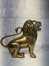 A side view of a regal brass lion statue with a detailed mane, open mouth, and tail curving upwards, depicting strength and majesty.